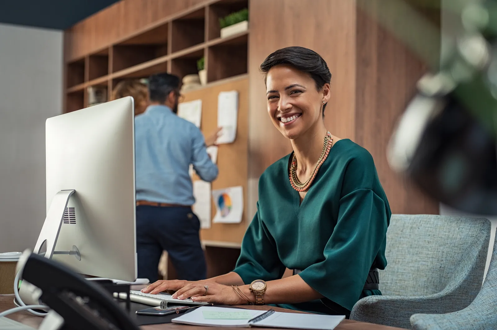 Office Manager Pop-In souriante à son poste de travail